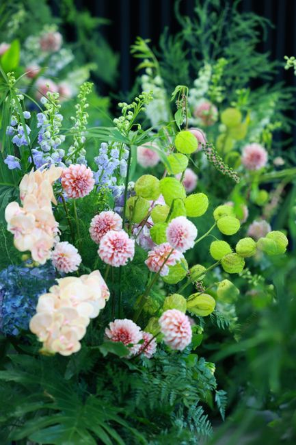 A lush floral arrangement featuring soft pink and cream hydrangeas, delicate pink pom-pom chrysanthemums, and green billy ball flowers with round, bright green seed heads. The bouquet is complemented 